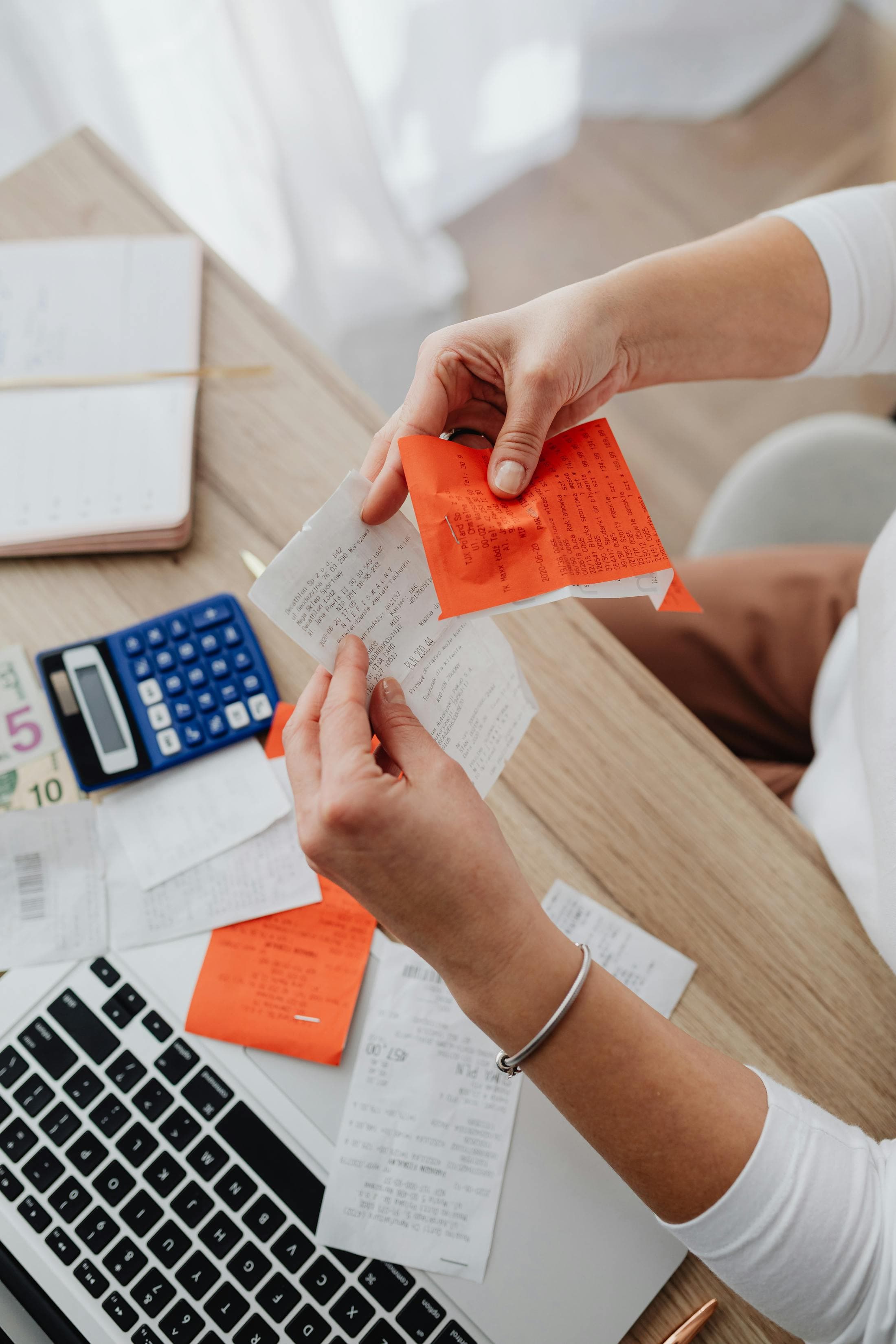 Receipts, a calculator, and notes spread across a desk.